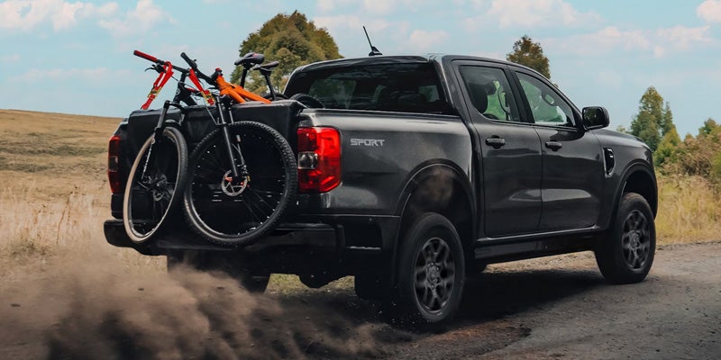 2026 Ford Ranger driving on a dirt road with bicycles in the truck bed