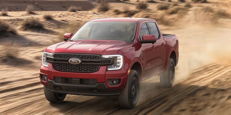 2026 Ford Ranger Raptor driving quickly across dusty off-road terrain