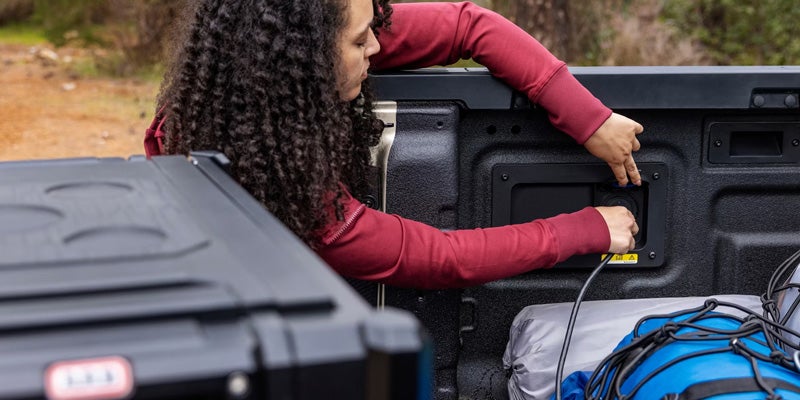 Hand plugging a cord into the in-bed outlet of a 2026 Ford Ranger